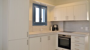A modern kitchen with white cabinets, a built-in oven, and a coffee maker.