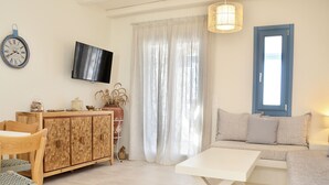 A living room with a sofa, a TV, a wooden cabinet, and a dining table.