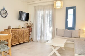 A living room with a sofa, a TV, a wooden cabinet, and a dining table.