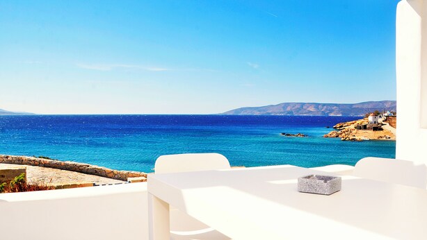 A seaside view from a white room with a stone wall and a table with a salt container. - Villa Amorgos, Sohoro Koufonisia (Koufonisia)
