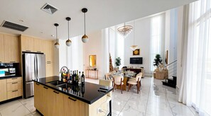 Een moderne keuken met een centraal eiland, een eethoek met stoelen, een kroonluchter en een televisie.