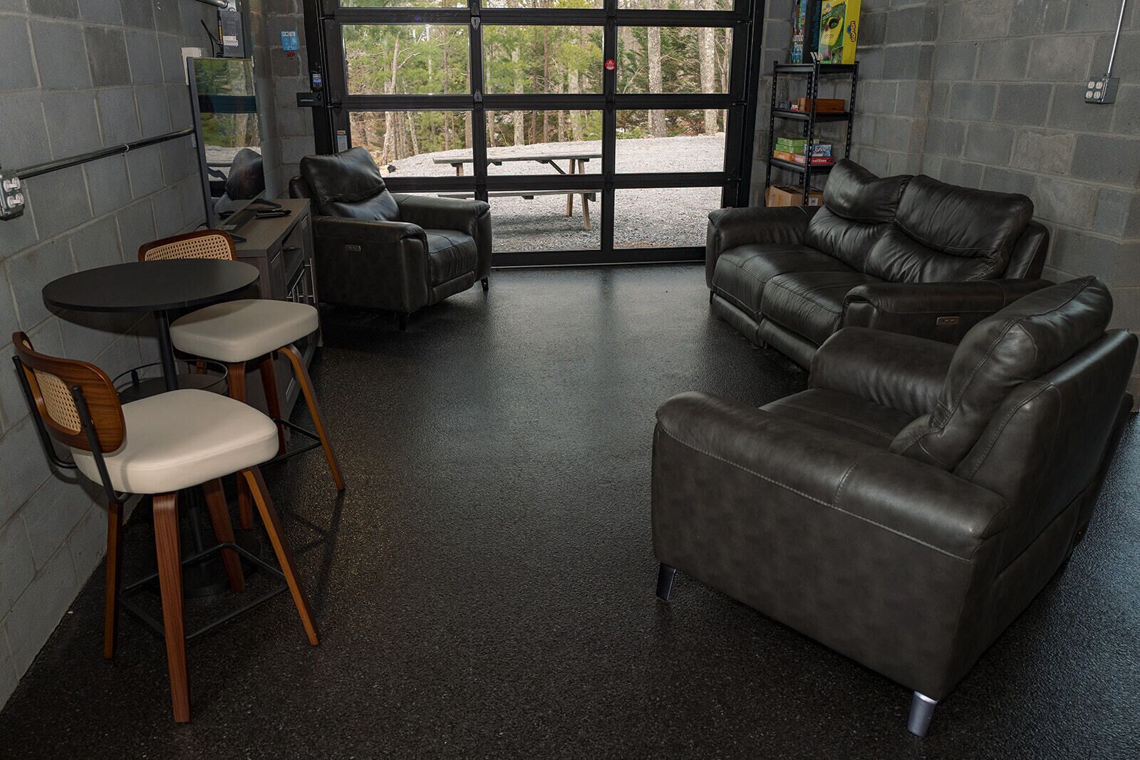 A room with a leather sofa, two chairs, a small table, and a large window.
