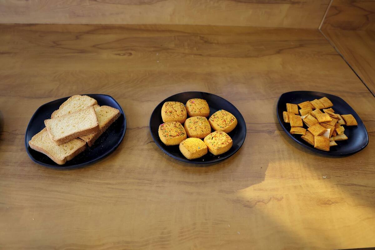 Three black plates with different food items on a wooden table.