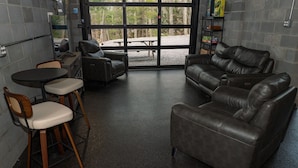 Una habitación con sofá de cuero, dos sillones, una mesita y un ventanal grande.