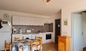 A compact kitchen with white cabinets, a dining table with chairs, a microwave, a coffee maker, and a small oven. - House with South-Facing Enclosed Garden (La Tranche-sur-Mer)