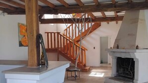 Un interior amplio con una escalera de madera, una chimenea y una zona de bar.