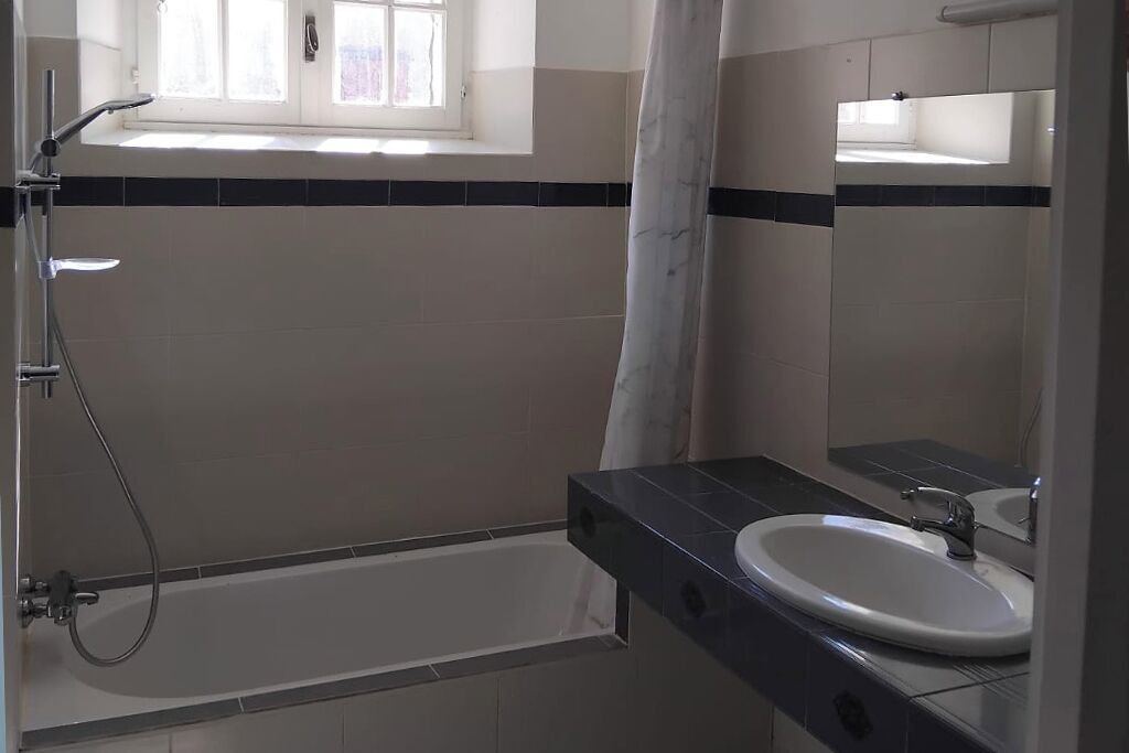 Ein Badezimmer mit Badewanne, Dusche, Waschbecken und Fenster.
