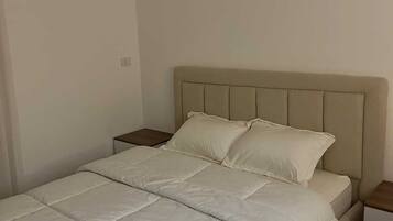 A bedroom with a bed, two nightstands, and a headboard.