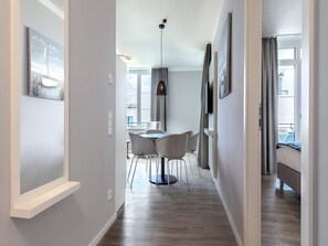 A modern hotel room with a dining area, a ceiling fan, and large windows. - 4 Star Holiday Home in Travemunde (Lübeck)