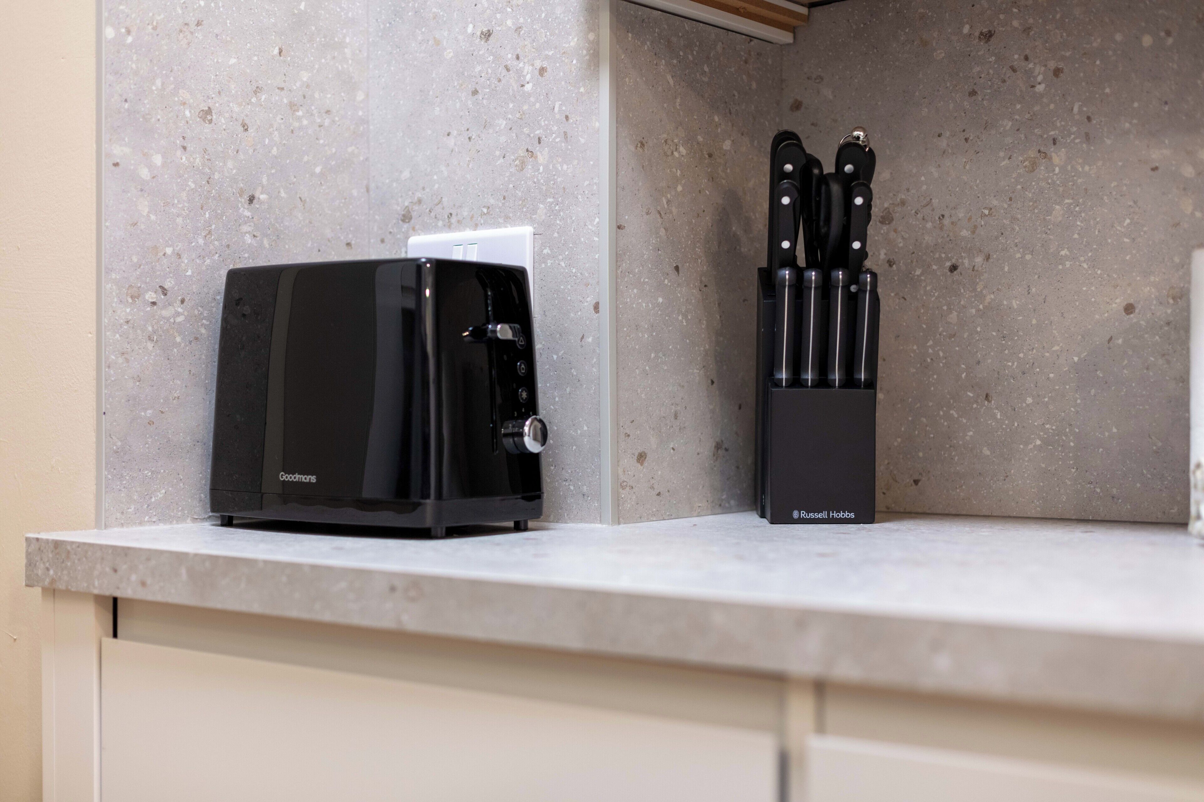 A kitchen counter with a coffee maker and a knife block.