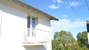 Un bâtiment blanc doté d’un balcon, d’une fenêtre et d’un toit visible.