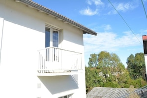 Un bâtiment blanc doté d’un balcon, d’une fenêtre et d’un toit visible.