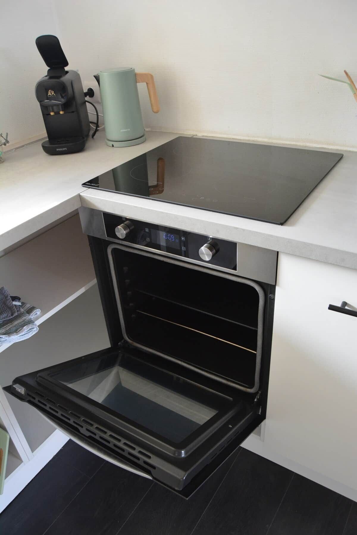 Een compacte keuken met een inbouwoven, een koffiezetapparaat en een waterkoker.