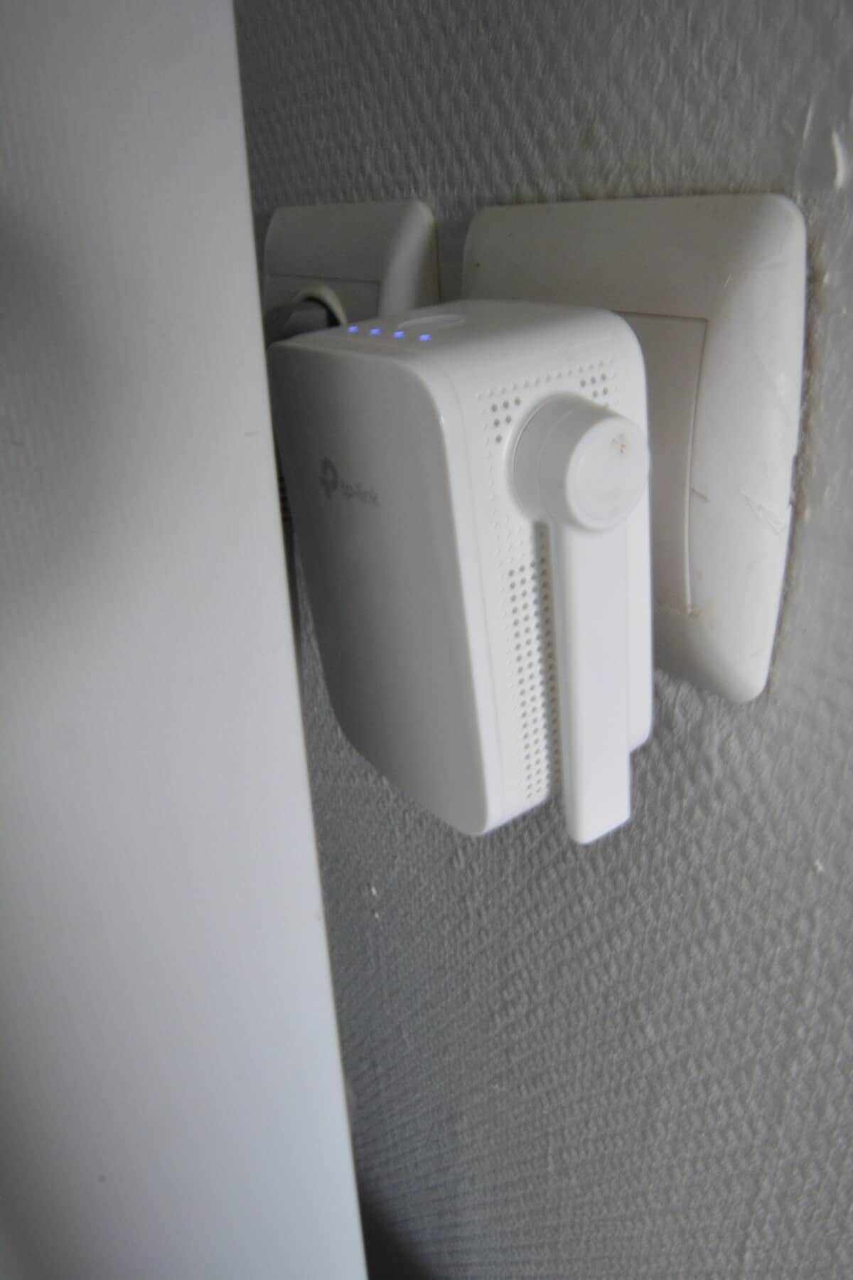 Un dispositivo bianco fissato al muro, dotato di una griglia circolare per l'altoparlante e di un cavo di alimentazione.
