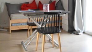 Un salon moderne comprenant une table à manger, des chaises, un canapé, un tableau et une grande fenêtre avec des rideaux.