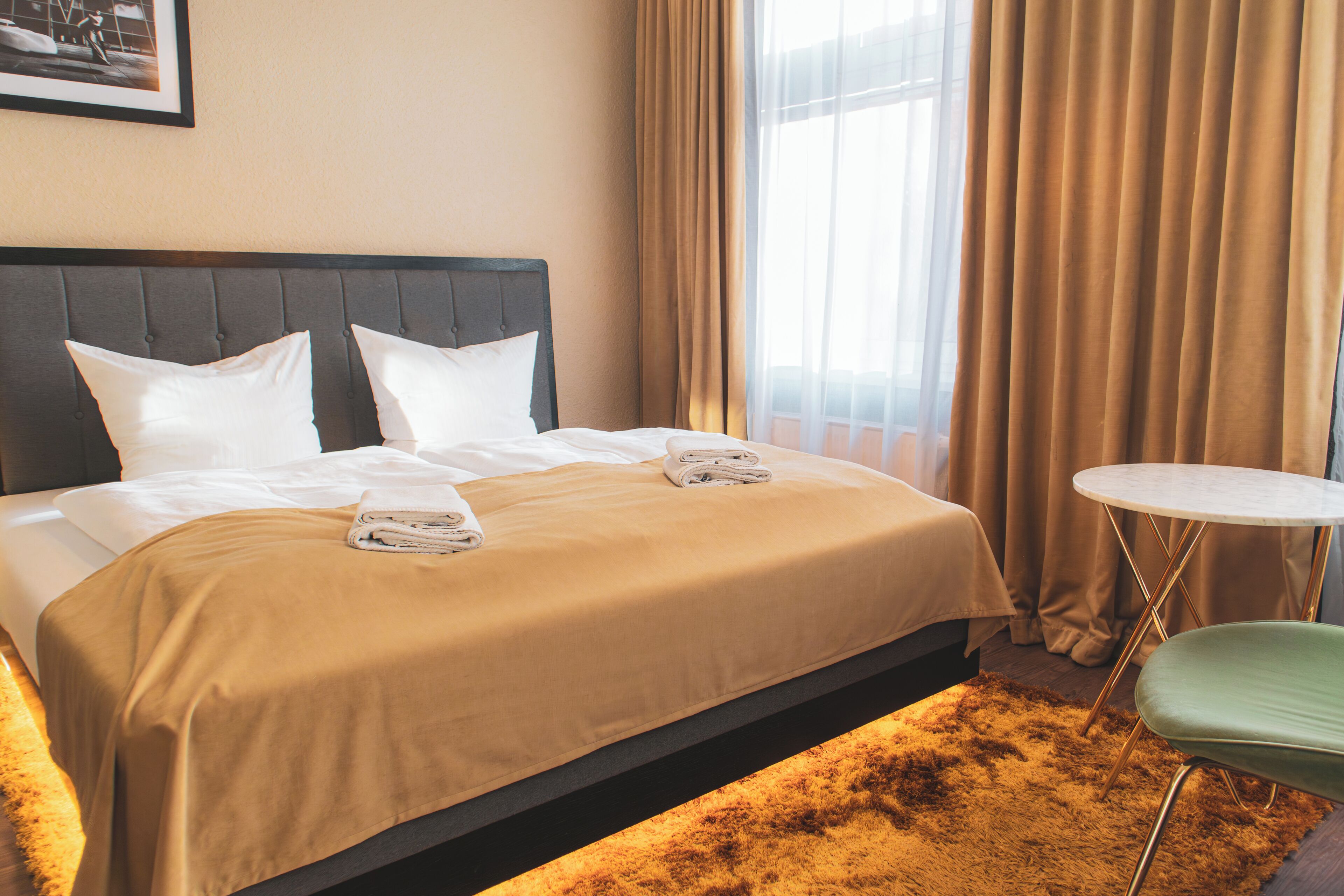 A hotel room with a bed, a round table, and a chair.