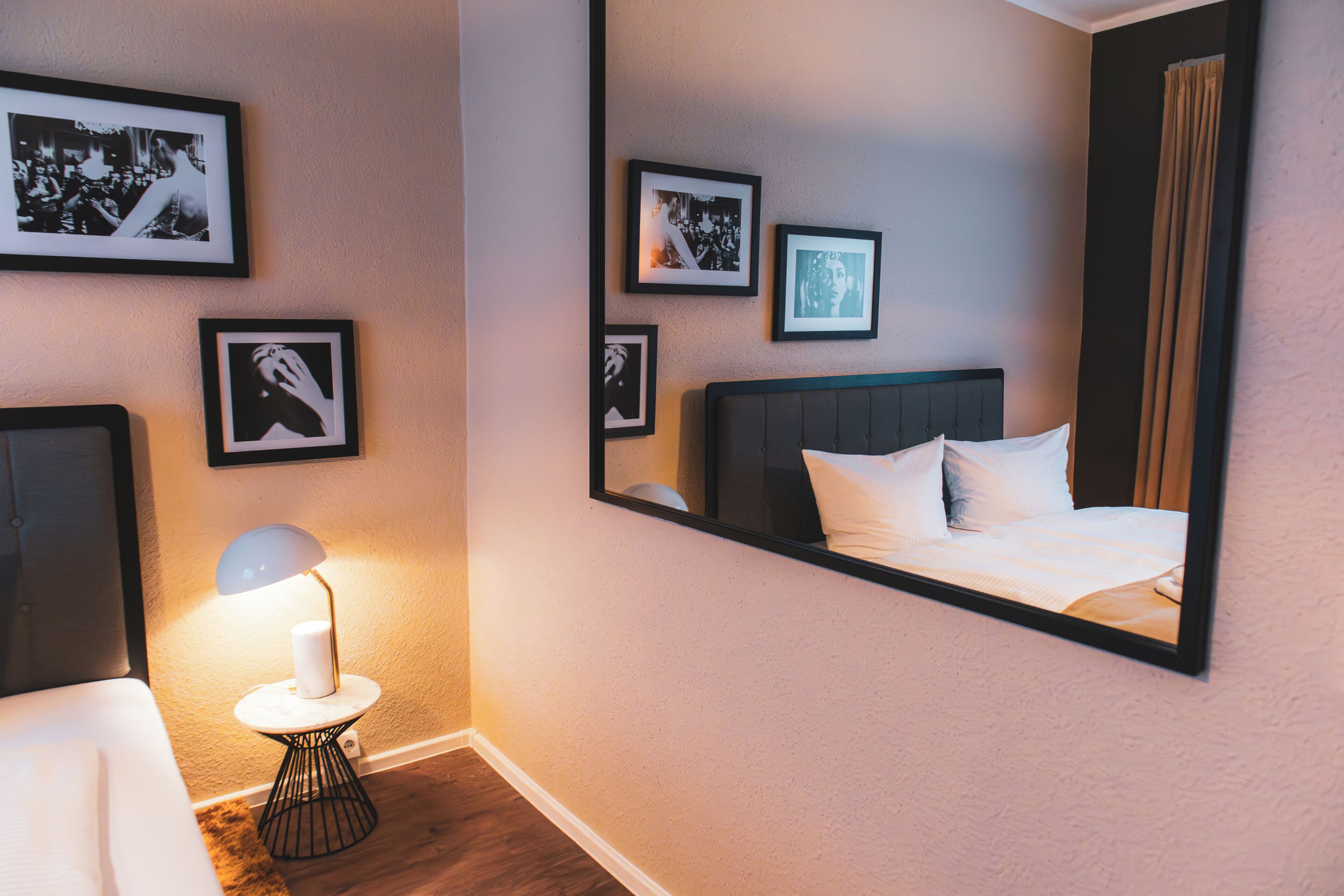 Een hotelkamer met een bed, een bedlamp, een ronde tafel en afbeeldingen in lijsten aan de muur.