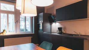 A compact kitchen with a dining table, chairs, a window with a view, and a built-in oven. - Cityloft Erfurt (Erfurt)