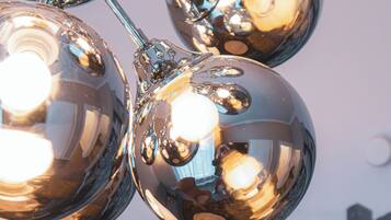 A close-up of shiny metallic spherical objects, likely part of a decorative installation, with a blurred background featuring traditional half-timbered buildings.