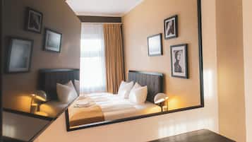 Een hotelkamer met een bed, nachtlampjes, een spiegel en ingekaderde foto's aan de muur.