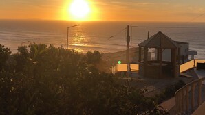 A sunset view over the ocean, a gazebo, and a street lamp.