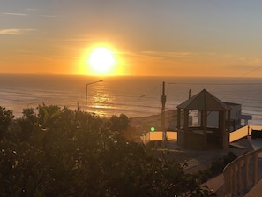 Une vue sur le coucher de soleil au-dessus de l’océan, un belvédère et un lampadaire.