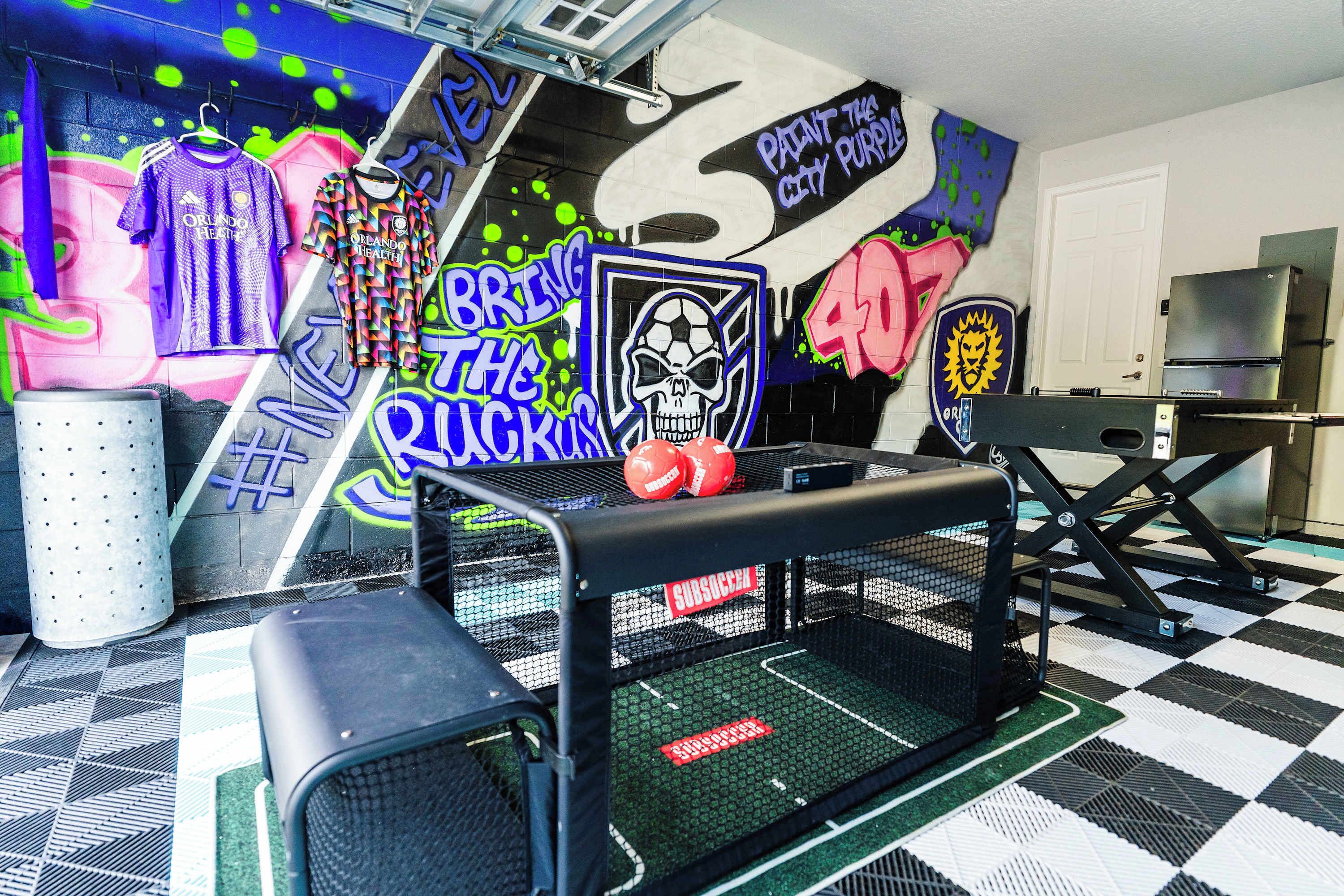 Une pièce avec un sol à carreaux, un canapé rayé noir et blanc, une petite table et un mur orné de graffitis et de maillots de sport.