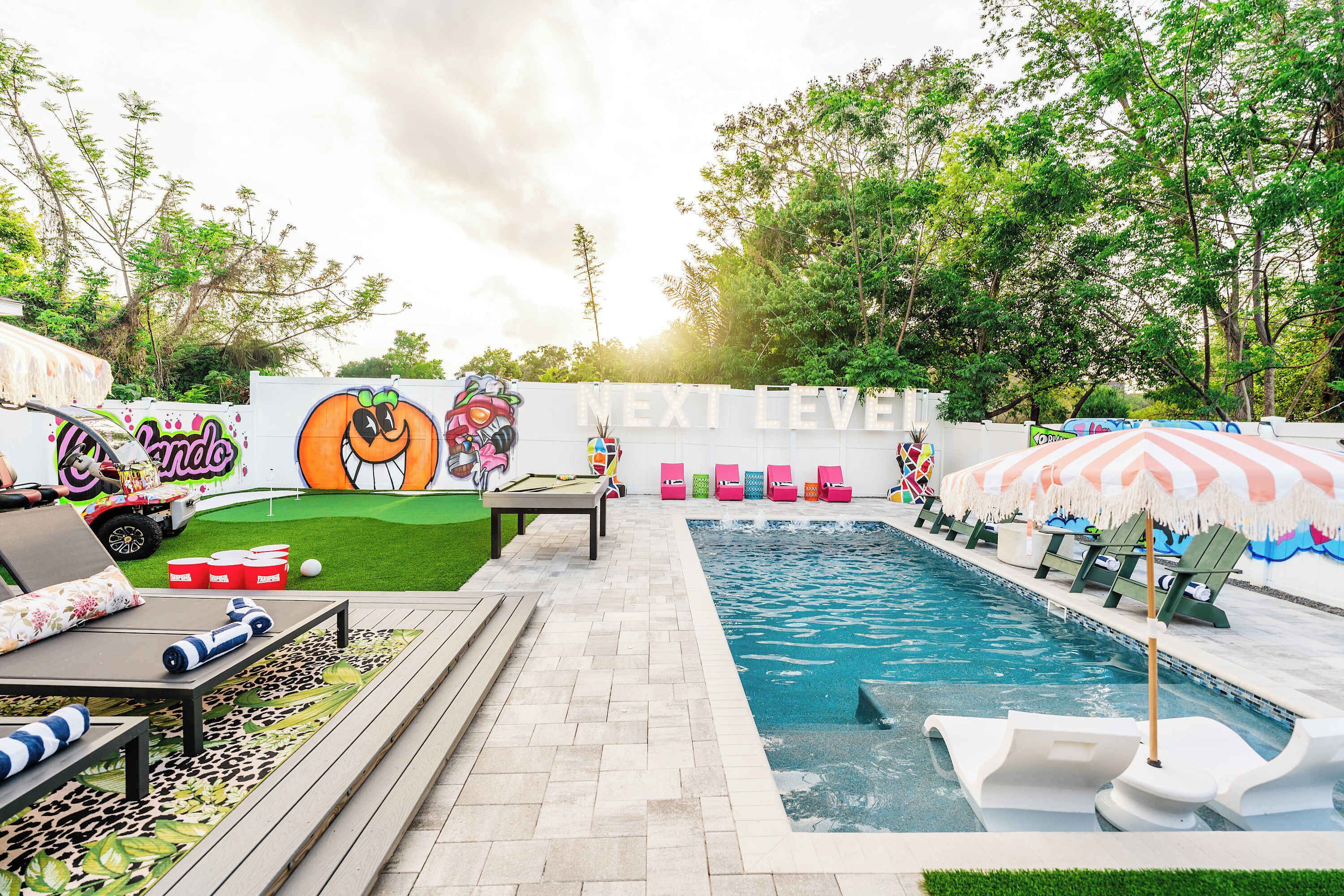 Un espace piscine avec des chaises longues, une table et une fresque murale.
