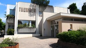 Ein modernes Gebäude mit der Aufschrift 'THERMIES' und 'FOR DAVON', das ein Hotel oder eine ähnliche Einrichtung kennzeichnet.