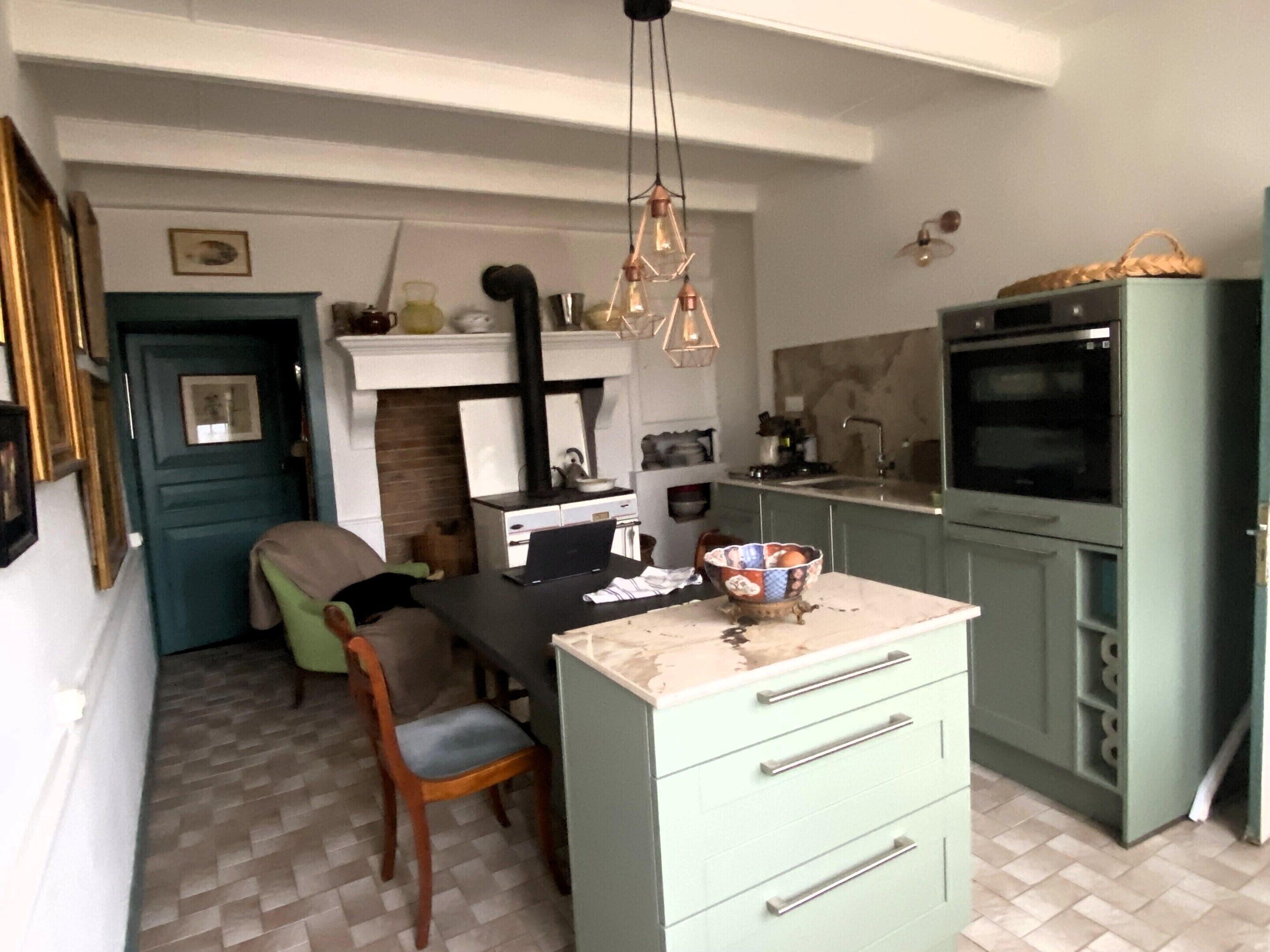 A compact kitchen with a dining area, a built-in oven, and a hanging light fixture.