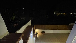 Eine Treppe führt zu einer Dachterrasse mit Fliesenboden und Geländer.
