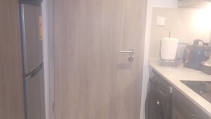 A kitchen with a 'NO SMOKING' sign, a refrigerator, a microwave, and a washing machine. - Executive Studio Room at Bantree Apartments,Accra Airport City (Accra)