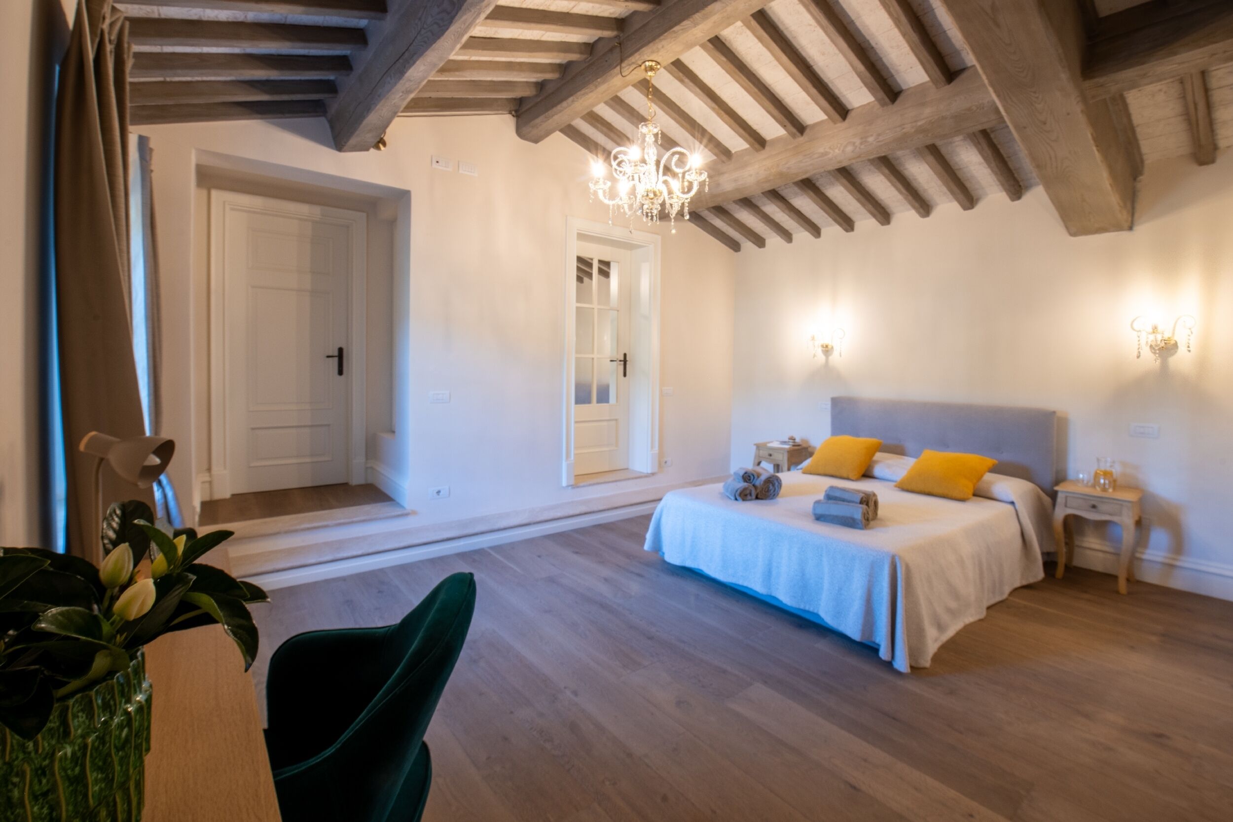 A bedroom with a bed, bedside tables, a chandelier, and a door.