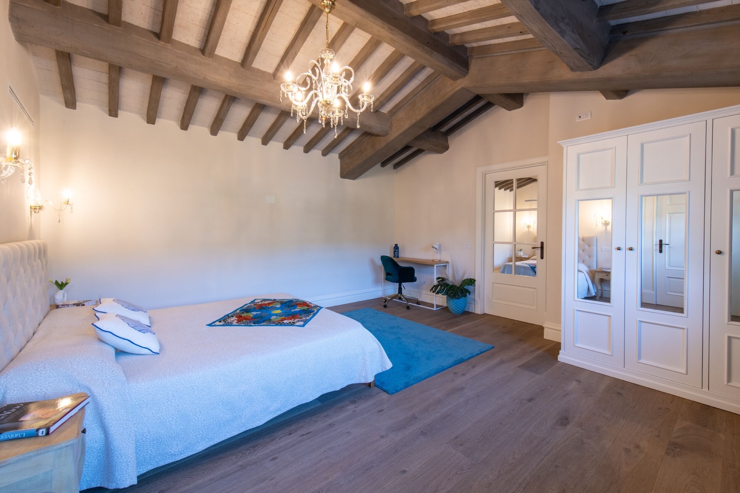 Ein Schlafzimmer mit Bett, Schreibtisch, Stuhl, Kleiderschrank und einer Chandelier.