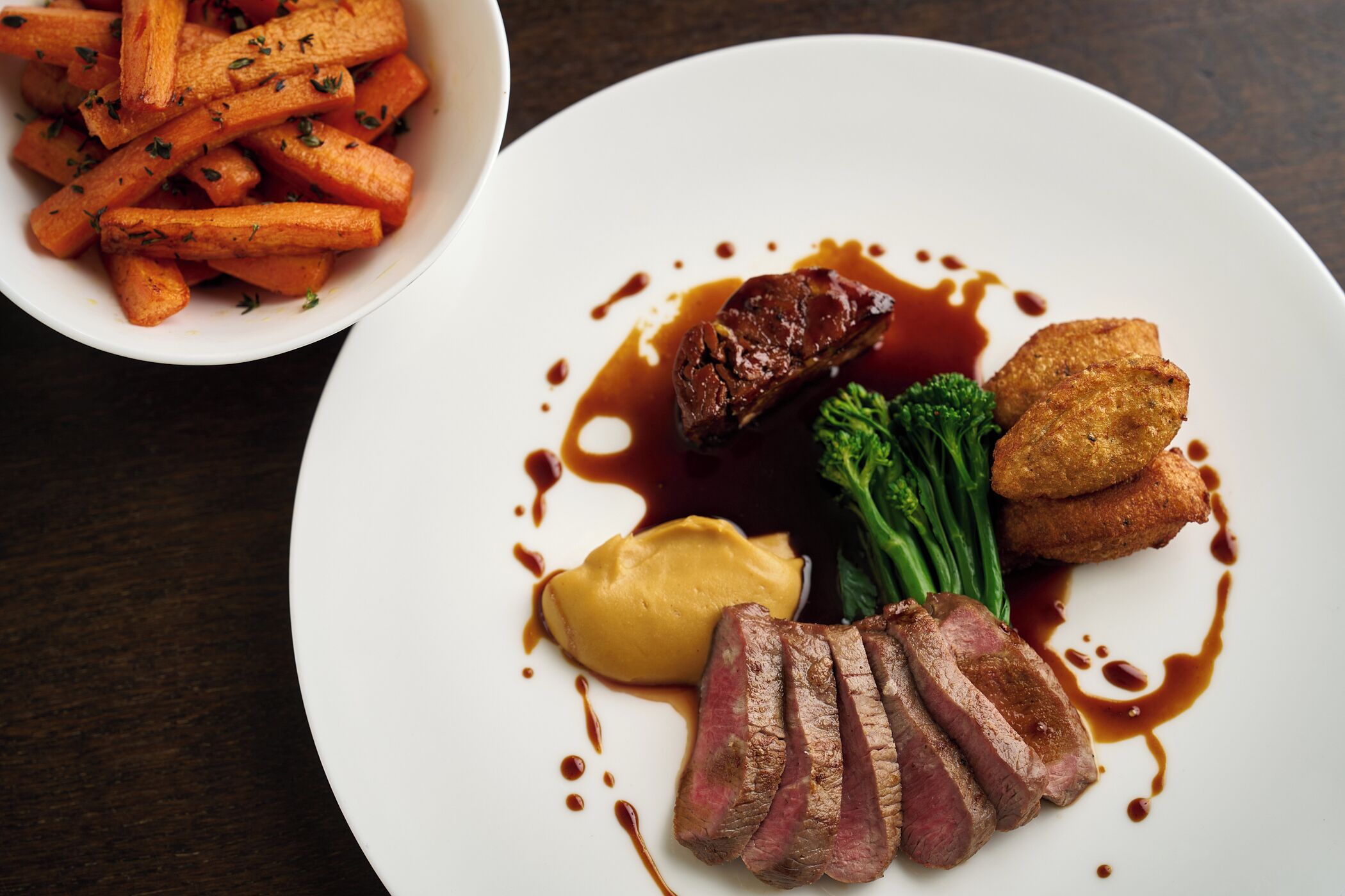 A plate of food with steak, fries, and a side dish.