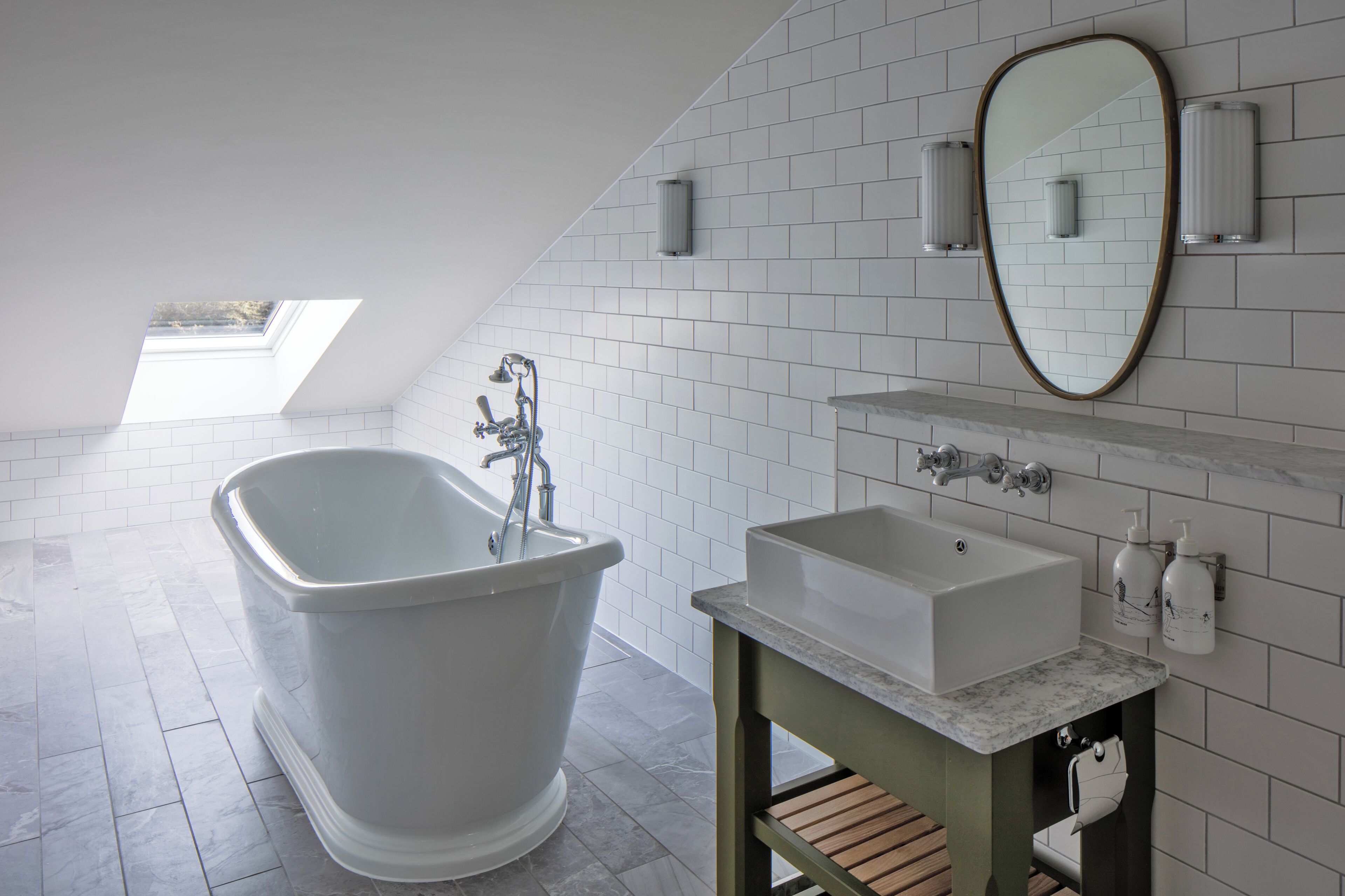 Ein modernes Badezimmer mit einer freistehenden Badewanne, einem Waschbecken, einem Spiegel und einem Oberlicht.