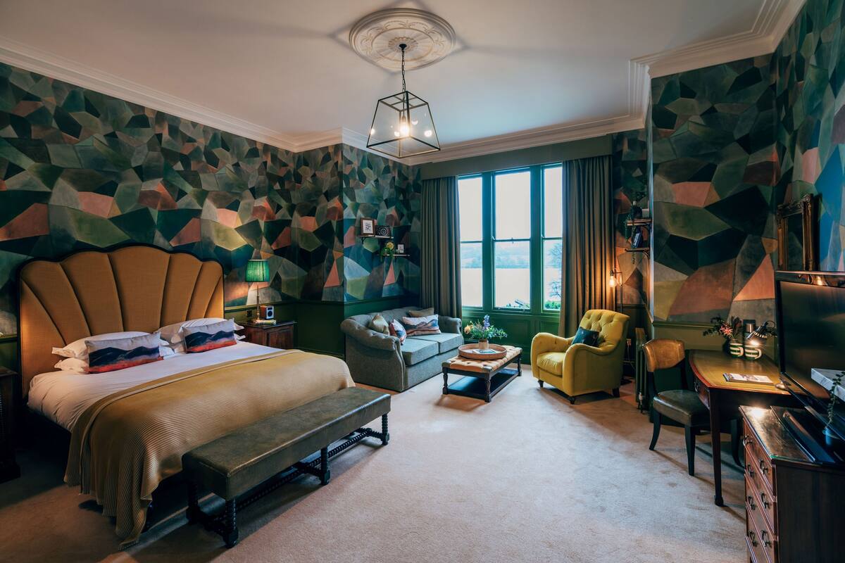 Una habitación de hotel con una cama grande, un sofá, un sillón amarillo, un escritorio y un televisor.