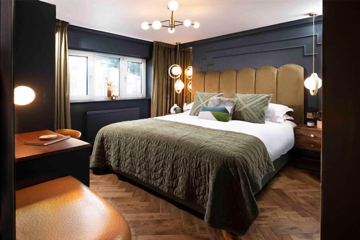 Un dormitorio con cama, mesitas de noche, ventana y una silla.