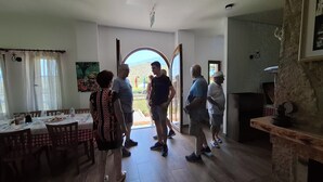 A room with a dining table, chairs, a painting, and a view through an open door. - Agroturizem Dr Bizhga (Picar)