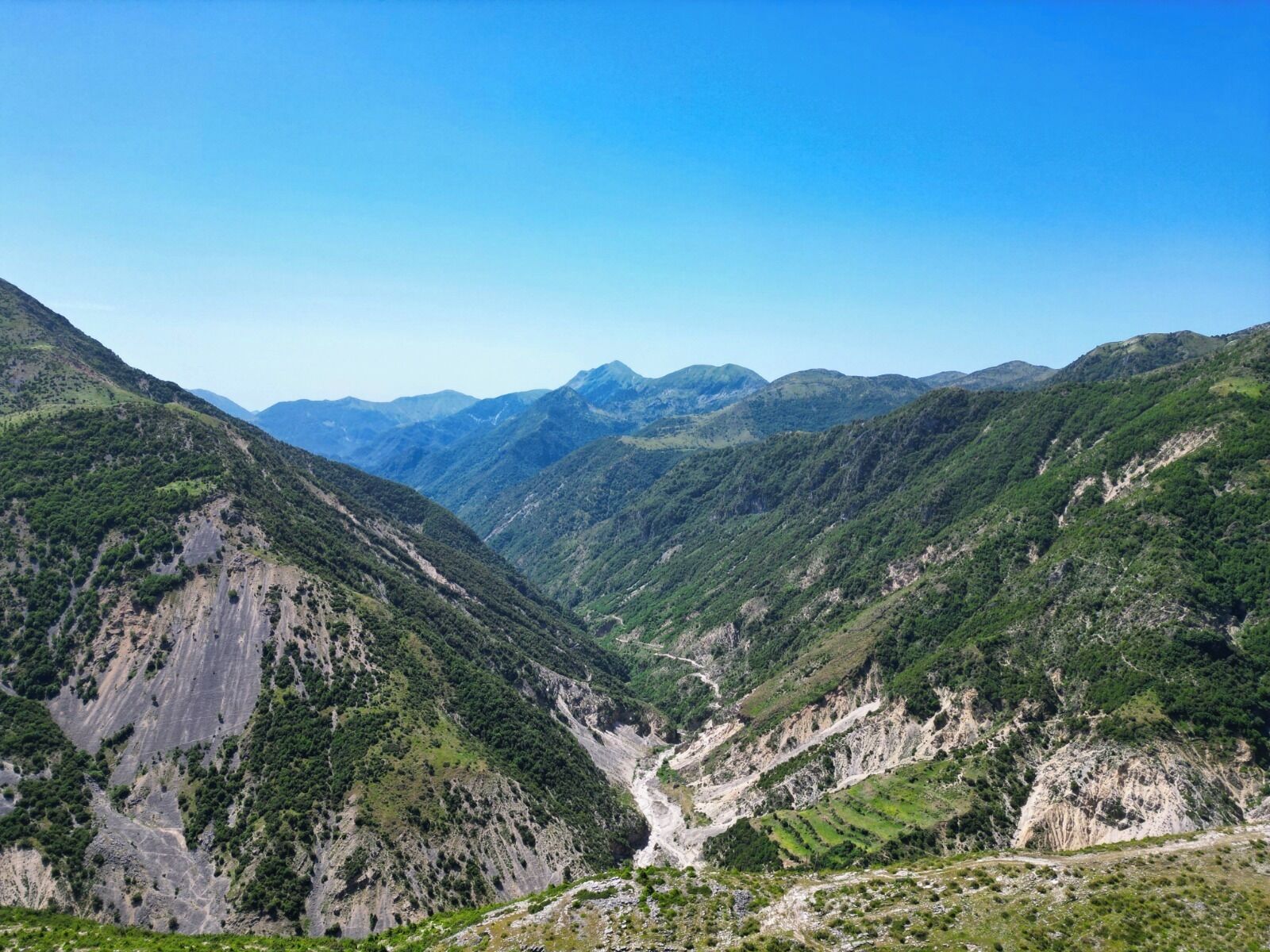 A mountainous landscape with a valley and distant peaks.