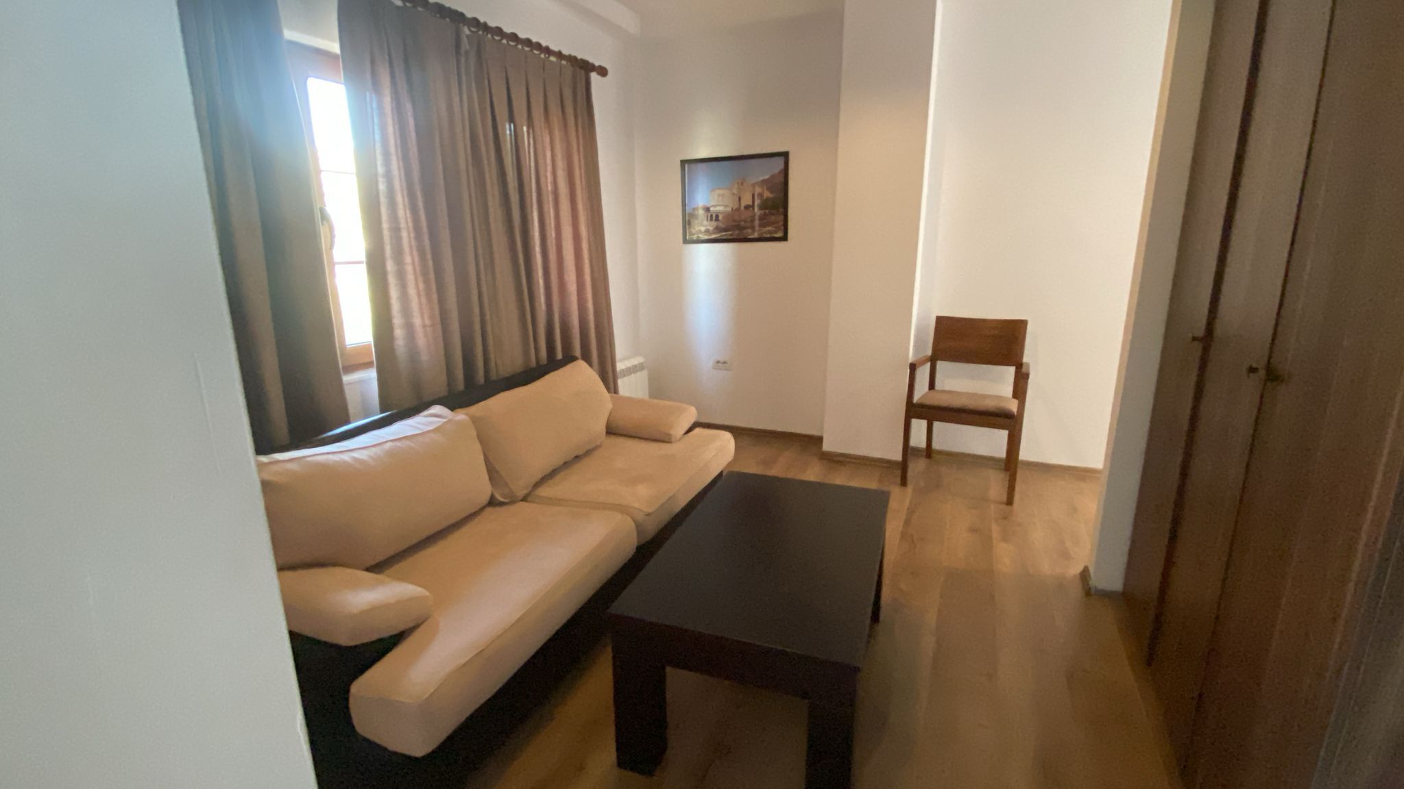 Ein Wohnzimmer mit einer Couch, einem Couchtisch, einem Sessel und einem Bild an der Wand.