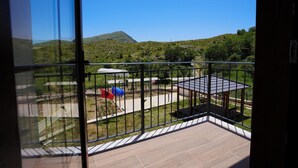 A balcony with a view of a green landscape, a small pavilion, and a flag. - Agroturizem Dr Bizhga (Picar)