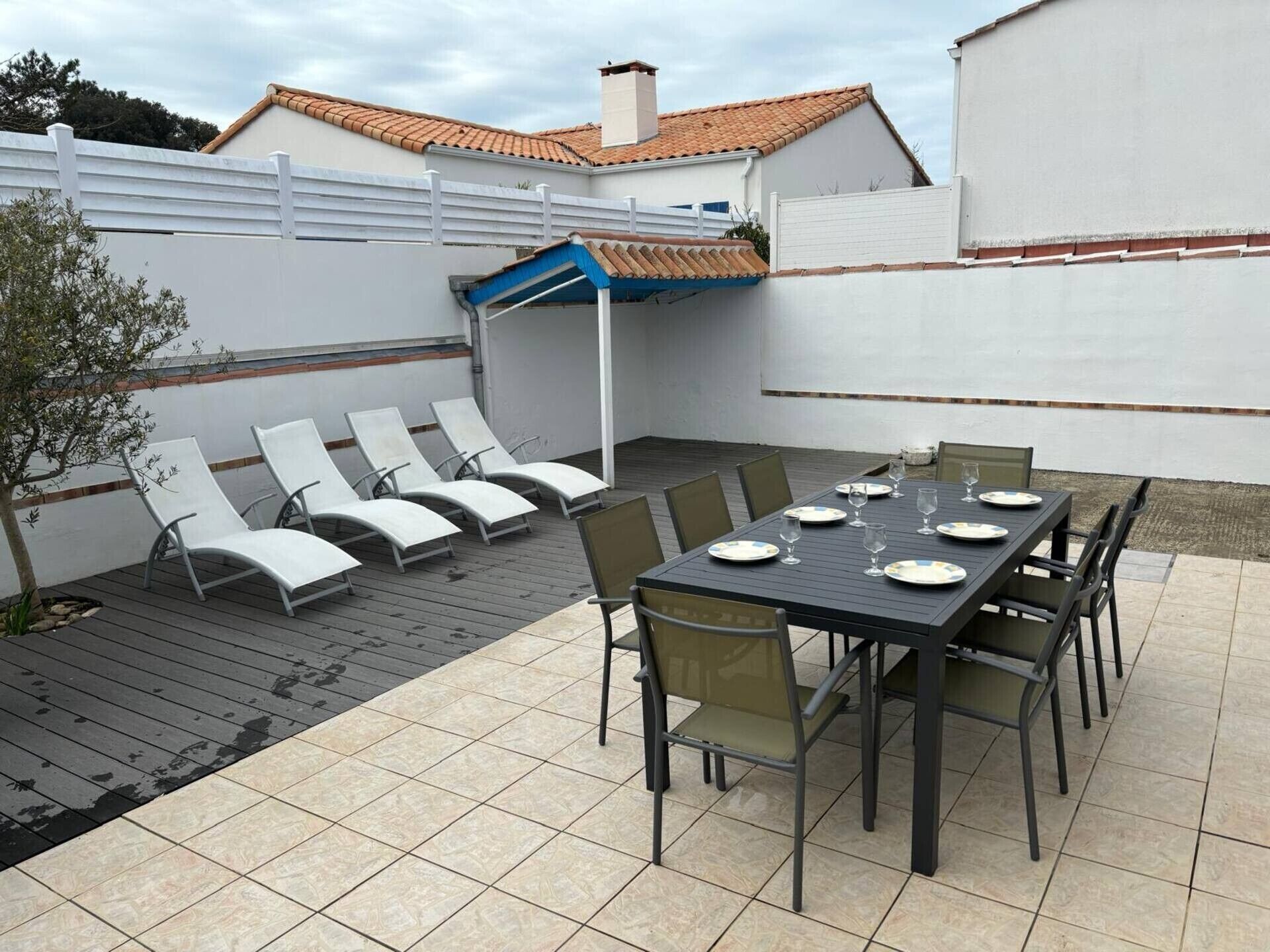 An outdoor patio with a table set for dining, lounge chairs, and a covered seating area.