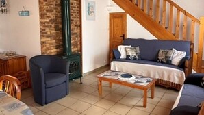 A cozy living room with a wooden ceiling, a sofa set, a coffee table, and a fireplace. - Maison Malovyn: Quiet House Near Beach and Forest (La Tranche-sur-Mer)