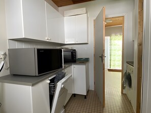 A compact kitchen with a microwave, toaster, and washing machine. - La maison des ombrines – Close to Phare Beach (La Tranche-sur-Mer)