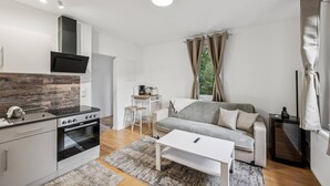 Un espacio habitable compacto con kitchenette, un sofá, una mesa de centro y zona de comedor.
