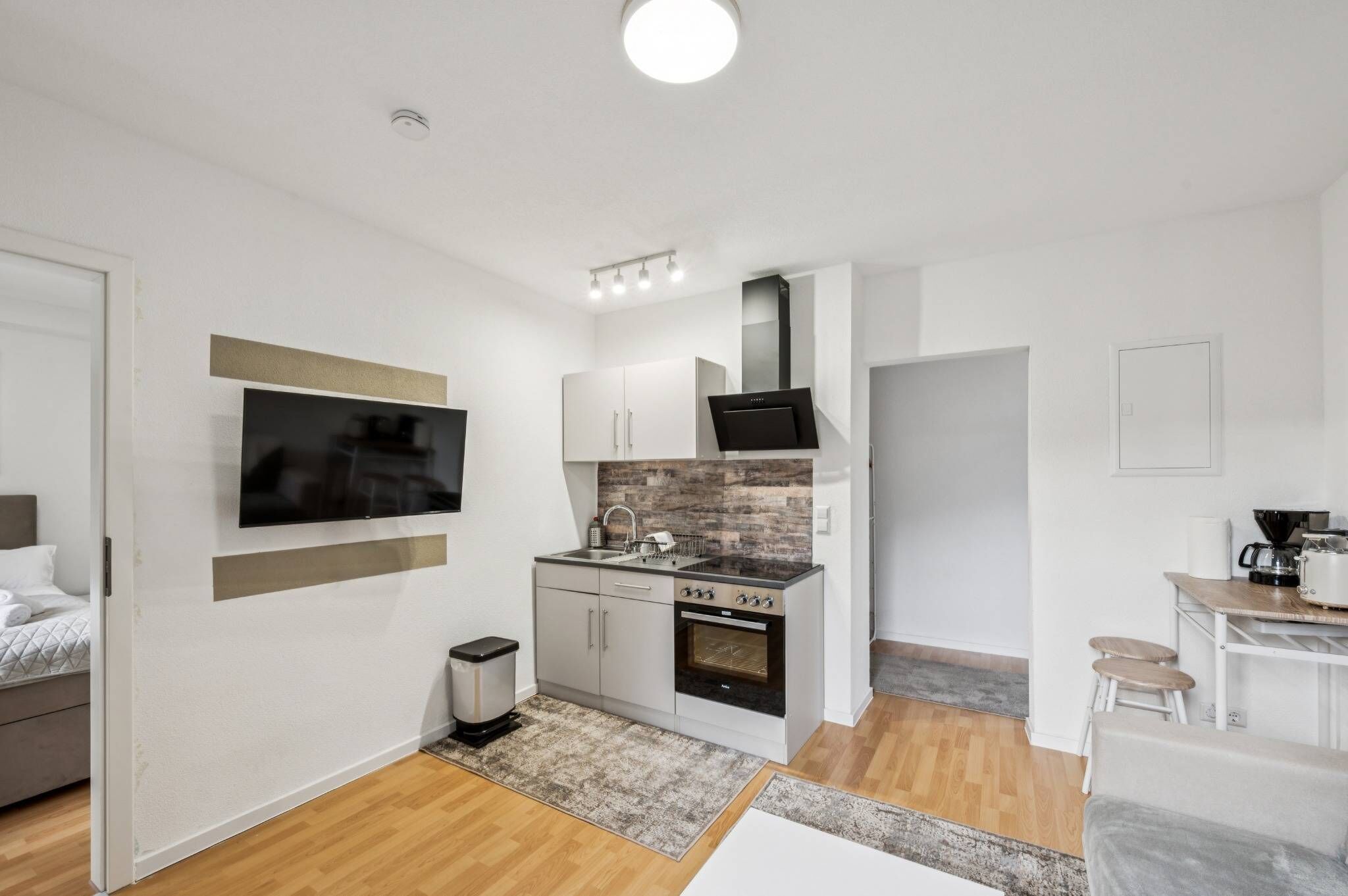 A compact kitchen with a flat-screen TV, a stove, and a microwave.