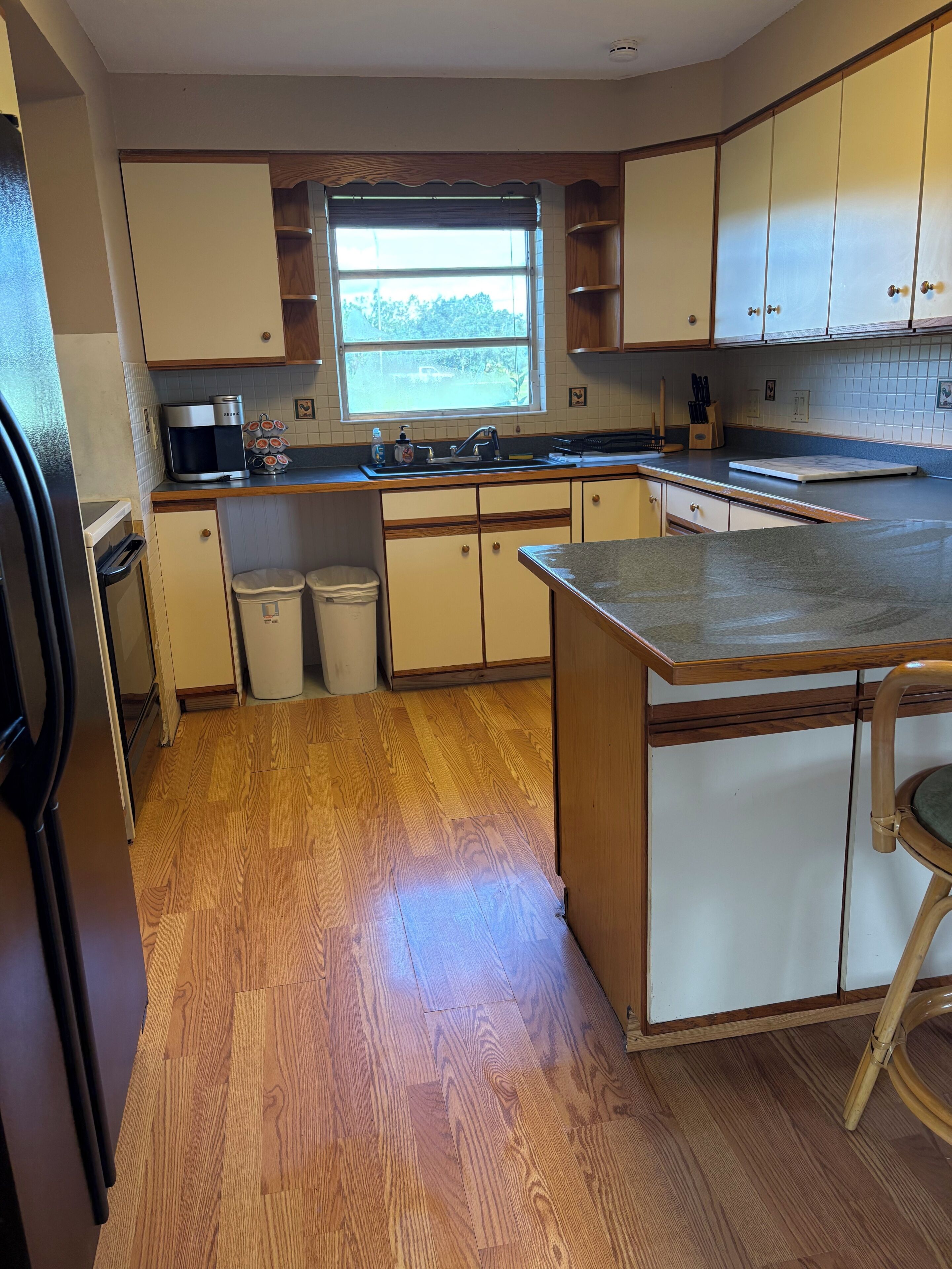 Une cuisine avec des meubles de rangement en bois, une cuisinière encastrée et une fenêtre.