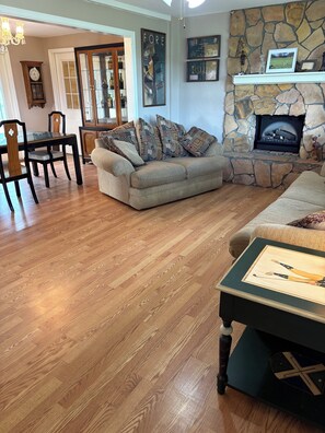 A living room with a stone fireplace, a dining area with a wooden table and chairs, and a cozy sofa. - Relaxing Punta Gorda Getaway 3BR, Kayaks, Outdoor Oasis (Punta Gorda)
