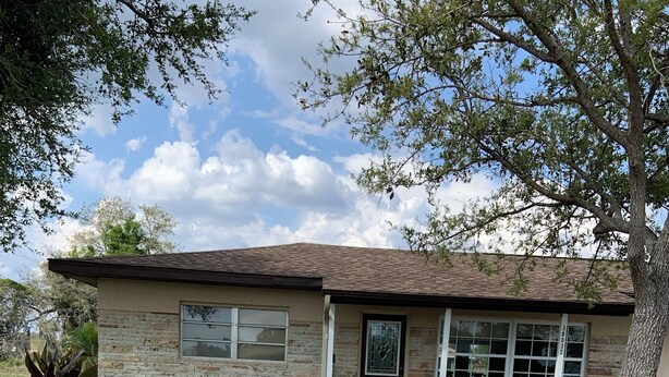 A single-story house with a brick exterior, a front porch, and a small front yard with scattered leaves. - Relaxing Punta Gorda Getaway 3BR, Kayaks, Outdoor Oasis (Punta Gorda)